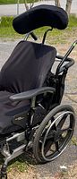 Close-up side view of the black seat and headrest of the wheelchair, showing padding and adjustable backrest.