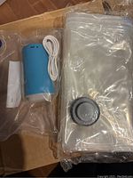 Blue and white portable vacuum suction machine with plastic vacuum seal bags for travel storage