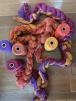 Colorful twisted cotton yarn skeins and spools in red, orange, yellow, purple on wooden floor.