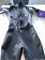 Front view of black and purple Body Glove women's wetsuit laid flat showing front zipper and branding