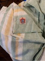 Green, yellow, and white striped wool blanket showing Ayers Canadian product label with maple leaf