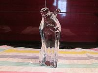 Front and side view of Baccarat crystal figurine of wise man with lamb on shoulder, showing clear transparent form and detailing.
