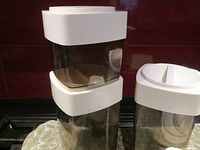 Two tall transparent smoky plastic containers stacked, ivory lids on top.