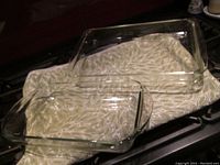 Two clear glass casserole dishes side by side on patterned cloth, one slightly larger than the other