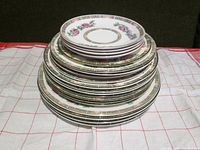 Stacked view of 20 John Maddock & Sons Indian Tree china plates showing different sizes and edge designs