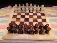 Onyx chess board showing whole set with white and dark brown pieces on the board.