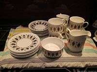 Full set displayed on cloth showing cups, saucers, small plates, cream jug, sugar bowl, and serving tray.
