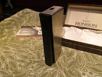 Ronson Eurolite lighter upright on a green fabric, showing silver metal with black side panel.