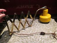 Photo showing the entire lamp with the metal scissor arm extended, yellow metal lamp head, and brown power cord with toggle switch.