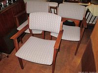 Front view showing all three mid-century modern armchairs with wood frames and upholstered seats and backs.