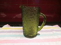 Front and side views of a green textured glass pitcher showing handle and spout