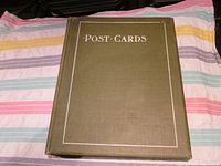 Front cover of a green vintage postcard album with 'POST CARDS' embossed in silver.