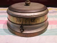 Front view showing tape measure numbered dial and pointer at 12 o'clock.