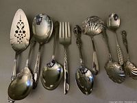 Top-down photo of all 10 unique silverplate serving utensils, showing different shapes and handle designs.