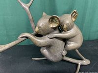 Front view showing two koalas hugging a branch, gold highlights visible in ears and nose