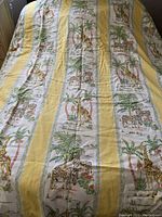 Full view of the duvet cover displaying yellow stripes and panels with giraffe and zebra animal designs, palm trees, and floral patterns.