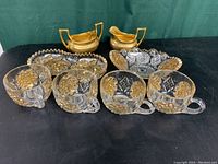 Photo showing the full lot including four pressed glass cups with gold trim, two EAPG dishes, and Stouffer's gold color cream and sugar set.
