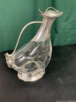 Front and side view of the crystal and pewter wine duck decanter showing the clear crystal body with polished pewter handle and lid.