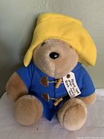 Front view of plush Paddington Bear sitting upright, clearly showing blue coat and yellow hat.