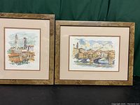 Pair of watercolor paintings framed in matching frames, showing French townscapes, placed side by side for full view.