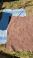 Photo showing two wool blankets laid on the ground, one blue and one brown, highlighting their size and overall condition.
