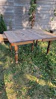 Full view of the oak antique dining table on grass outdoors revealing the rectangular tabletop and turned legs.