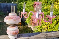 Pink glass chandelier with floral design oil lamp on wooden surface outdoors