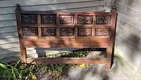 Full view of the Mexican hand carved wooden queen size bed headboard outdoors, showing its shape and structure.