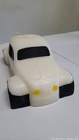 Front angle view of the VW Beetle candle showing white body, black windows, and yellow headlights.