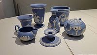 Full view of all seven Wedgwood blue jasperware ceramic items arranged on a table.