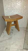 Side angled view of teak shower bench showing curved seat and angled legs