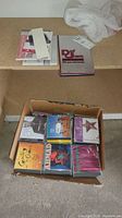 Box of assorted music CDs including colorful jewel cases and a Def Jam 10 year anniversary box set.