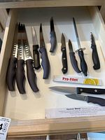 Full drawer view of 11 knives with varied blade types and handles along with Pro-Filet sharpener and Forever Sharp paper insert