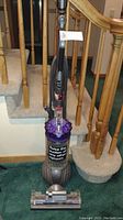 Full view of the upright Dyson DC65 Animal vacuum showing purple cyclone, grey ball base, and vacuum head assembly.