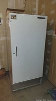 Full view of white upright freezer showing door, handle, and vent at bottom