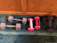 Photo of two 15-pound cast iron hex dumbbells and four neoprene dumbbells (2 pink 5 lbs, 2 red 8 lbs) on carpeted stairs in front of wooden cabinet.