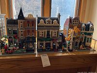 Row of interconnected modular buildings on window ledge showing all three assembled sections