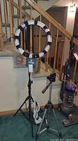 Full setup photo showing Diva Ring Light Super Nova mounted on tripod and additional tripod stand next to it with a vacuum cleaner in background.
