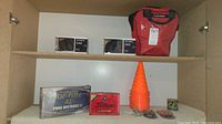 Photo of red mesh bag with bocce balls, two boxes of golf balls (Top Flite and Titleist), orange training cones, and small containers with sports items.
