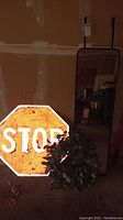Photo showing the official sized stop sign leaning against wall with wreath in front and mirror partially visible at back