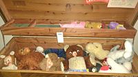 Wooden case filled with over a dozen assorted stuffed animals, some vintage with painted faces, varying sizes and colors.