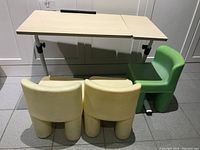 Front view of adjustable table with two beige and one green Little Tikes plastic chairs