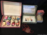 Photo showing all items: 8 colorful Chinese opera mask figurines in a box, packaged jade Buddha figurine in a decorative box, and reddish-brown clay teapot pendant with red cord.