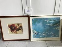 Two framed prints placed on floor against wall. One is a floral close-up, the other is a water lily scene print with signature and numbering.