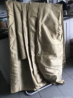 Photo showing multiple yards of gold-colored fabric draped, highlighting size and texture.