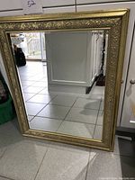 Full view of large rectangular mirror with gold glitter heavy ornate frame.