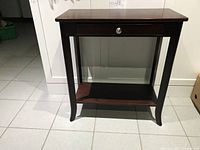 Front view of dark wood hallway table showing drawer and lower shelf