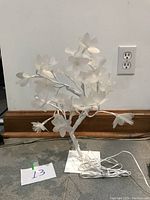 White flower branch lamp unlit showing flower shape, white petals, square base, and electrical cord.