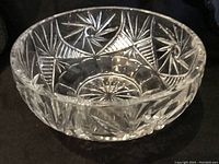 Side view of clear crystal bowl showing deep pinwheel and starburst cuts with scalloped edge.