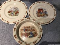 Three porcelain baby dishes with Bunnykins patterns on the surface with bunny motif border around edges